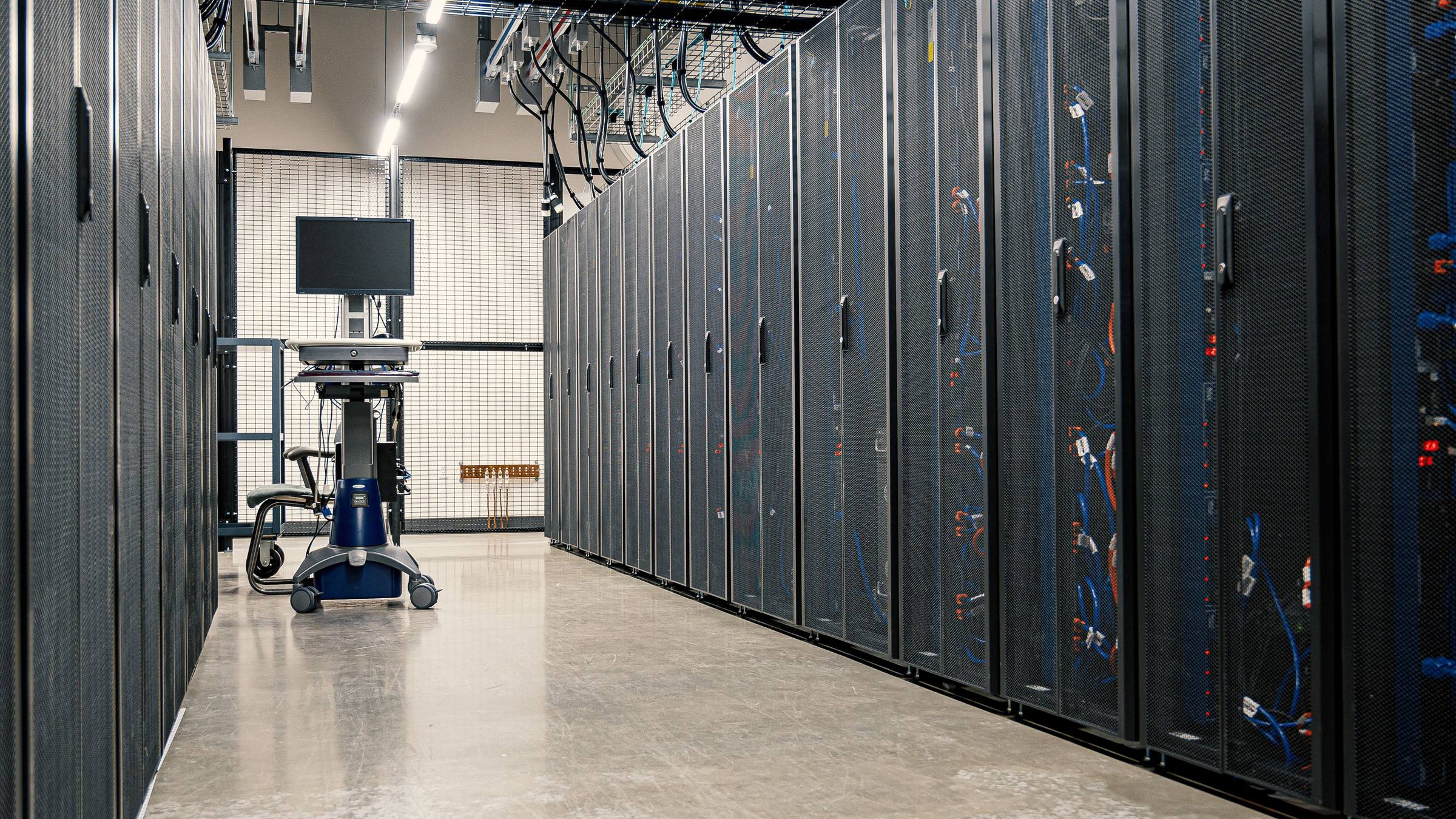 Aisle of server racks with a monitoring workstation