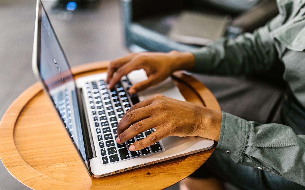 Hands typing on a laptop on a wooden table