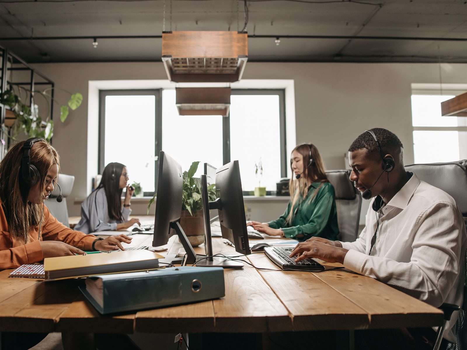 Support team with headsets working at computers in an open-plan office